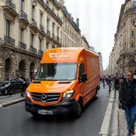 Fourgon de Parisian Express circulant rue animée de Paris